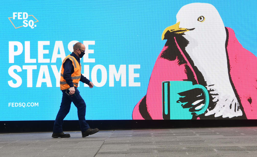A man passes a sign encouraging people to stay home in Melbourne on May 28, 2021, as the city's residents returned to a seven day lockdown to curb the spread of the Covid-19 coronavirus. (Photo by William WEST / AFP)