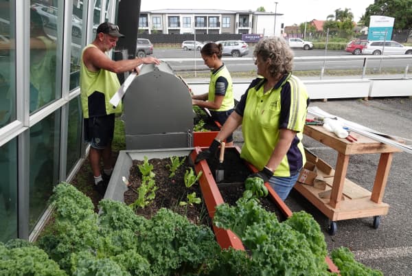 Rick Harper and Nike Rosenthal work on the strawberry planter box while Tracy Moore tends to the lettuce, herbs and kale.