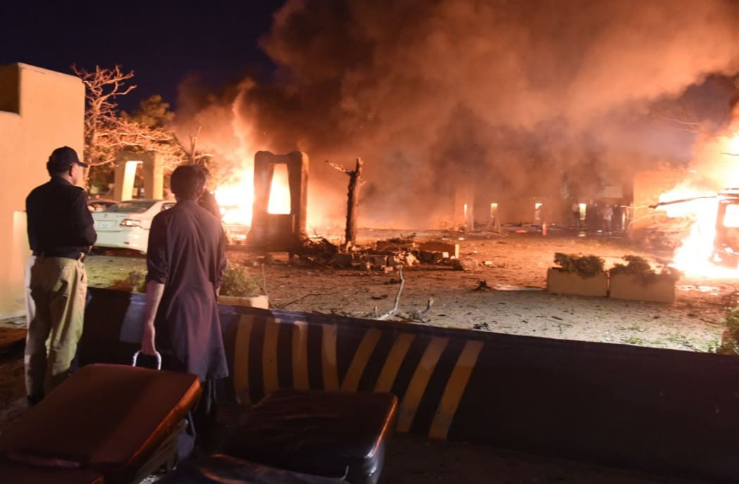 QUETTA,PAKISTAN-APRIL21: Law enforcers examining the scene after an bomb explosion as flames rise at Sereena Hotel in Quetta, Pakistan April21,202 .