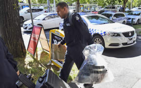 A Victoria Police forensic officer carries items to be loaded into a trailer outside the Italian consulate in Melbourne on January 9, 2019. Australian police are investigating the delivery of suspicious packages sent to foreign embassies and consulates in Melbourne and Canberra.