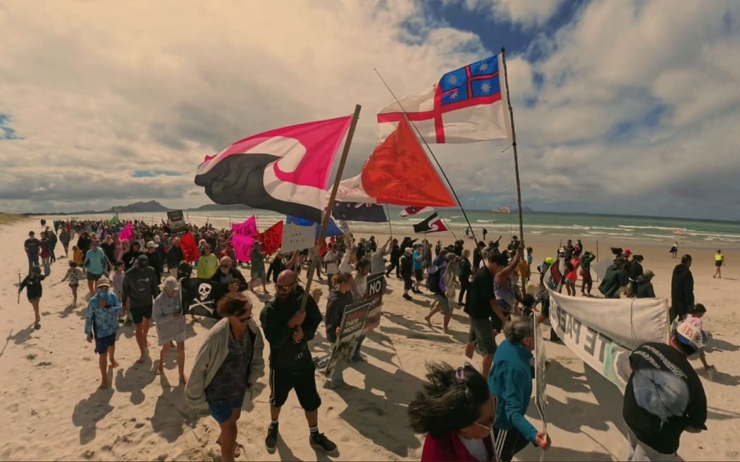 Protestors opposed to a sand mining proposal off Northland’s Bream Bay march down Ruakākā Beach.