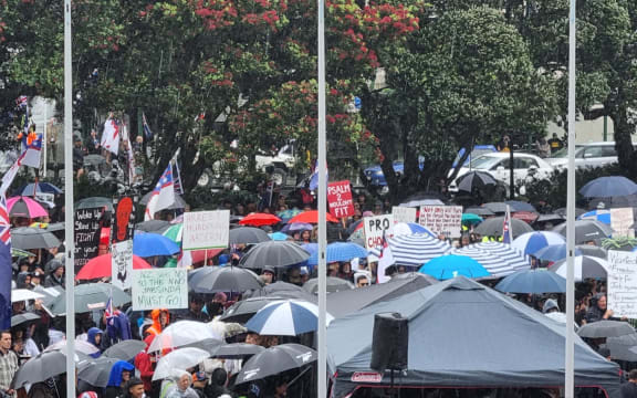 People protesting against Covid-19 vaccination mandates and restrictions take cover under umbrellas to shelter from the rain at Parliament grounds on 16 December, 2021.