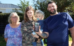 Isaac McCallum has an app on his cellphone so if he wanders off in a semi-conscious state before a seizure, family (from left) his mother Teresa and partner Abbie Willoughby, holding son Harrison, will be able to call police who can track his location.