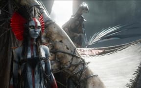 Varang is an alien-looking grey-skinned humanoid creature with a red and black headress.