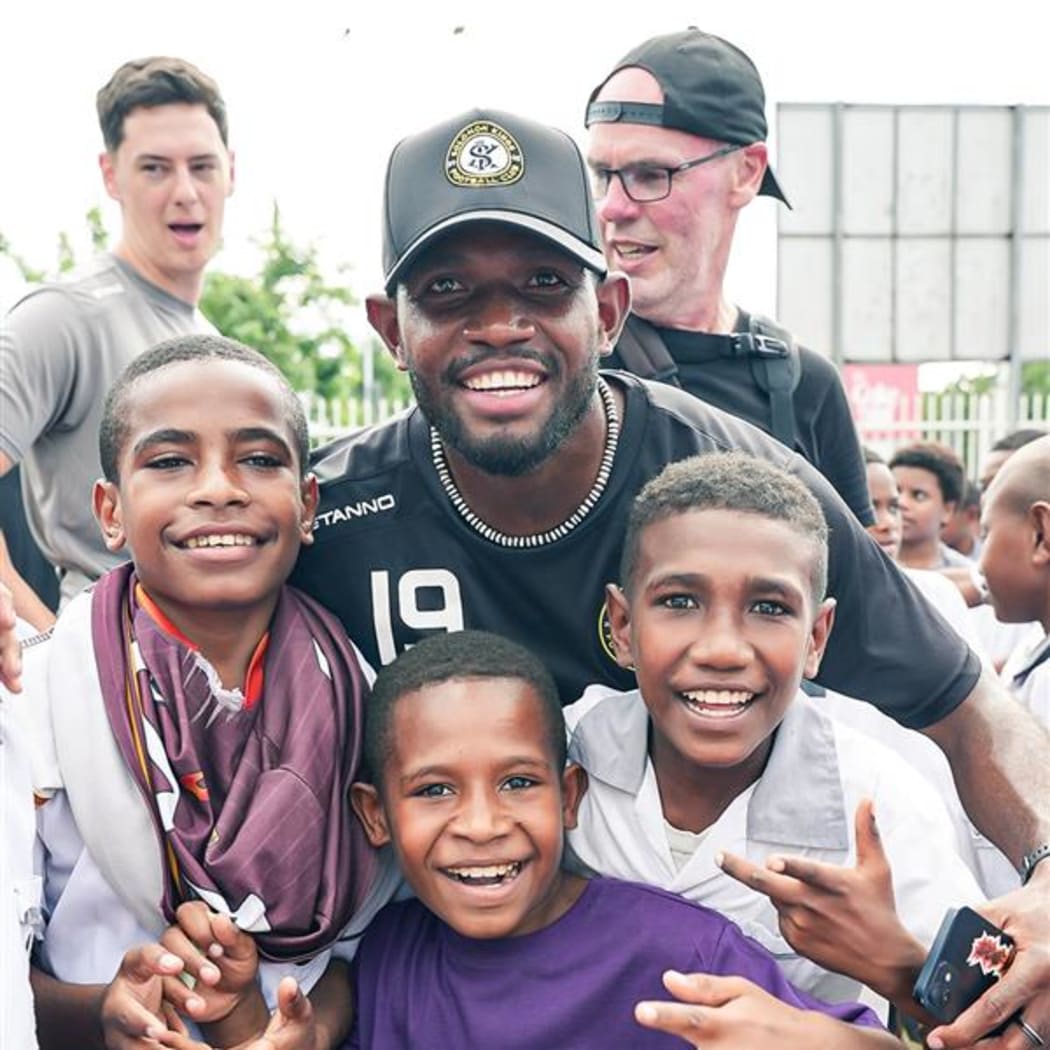Wardstrip Demonstration Primary School students with a Solomon Kings FC player during the team's school visit in Port Moresby on Thursday.