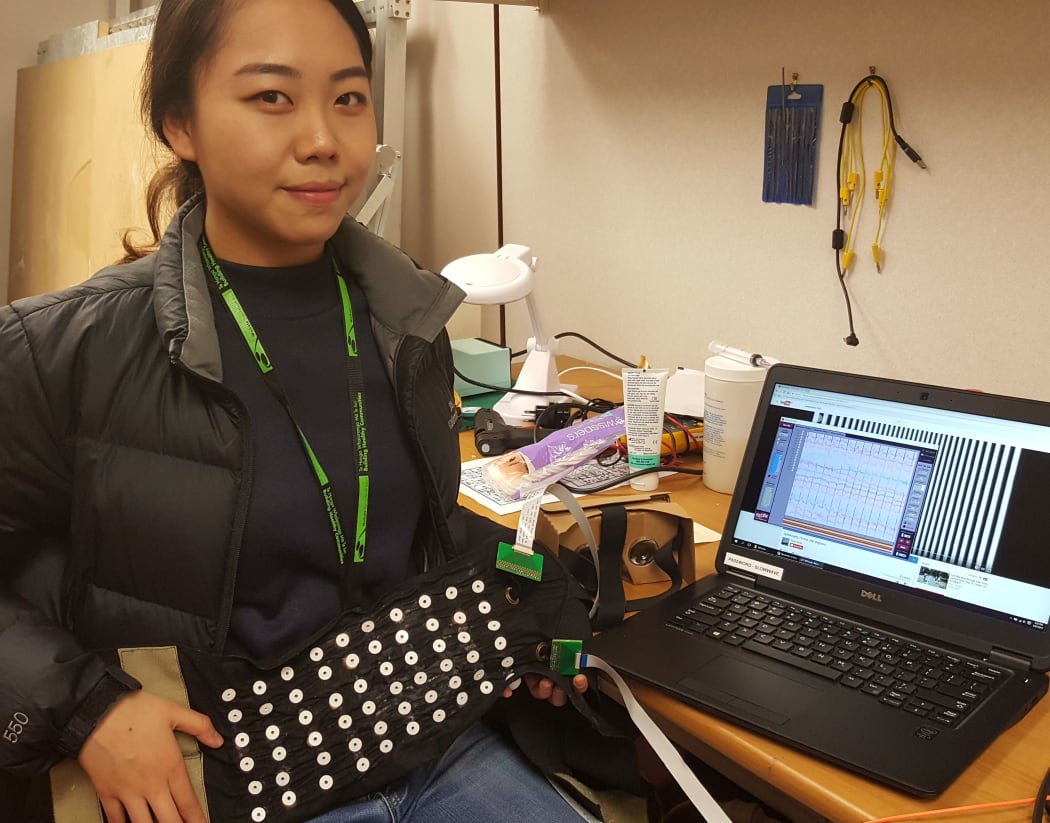 Sarah Jeong holding the electrogastrography belt, which is covered with electrodes to measure electrical signals from the gut.