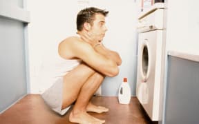 Teenage boy watching washing machine (Photo by ANSGAR WERRELMANN / Image Source / Image Source via AFP)