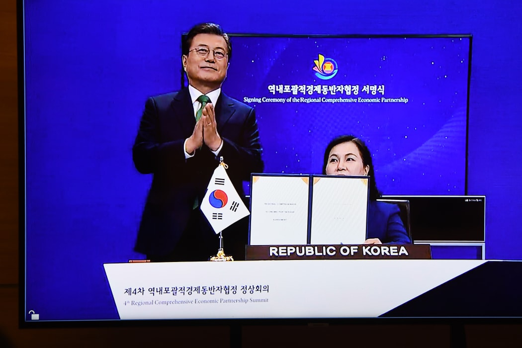 South Korea's President Moon Jae-in claps as Minister for Trade Yoo Myung-hee (right) holds up the signed RCEP agreement at the ASEAN summit held online in Hanoi on November 15, 2020.