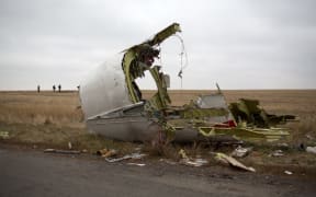 (FILES) In this file photo taken on November 11, 2014 Journalists walk behind parts of the Malaysia Airlines plane Flight MH17 as Dutch investigators (unseen) arrive near at the crash site near the Grabove village in eastern Ukraine, hoping to collect debris from the Malaysia Airlines plane which crashed in July, killing 298 people, in remote rebel-held territory east of Donetsk. - A Dutch court gives its verdict on November 17, 2022 in the trial of four men over the downing of Malaysia Airlines flight MH17 above Ukraine in 2014, as tensions soar over Russia's invasion eight years later. All 298 passengers and crew were killed when the Boeing 777 flying from Amsterdam to Kuala Lumpur was hit over separatist-held eastern Ukraine by what investigators say was a missile supplied by Moscow. (Photo by Menahem KAHANA / AFP)