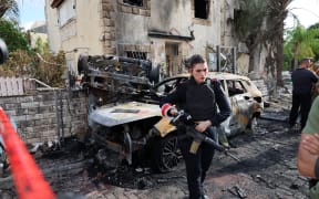 A member of the Israeli security forces stands guard inside a cordoned-off area in Kiryat Bialik in the Haifa district of Israel, targeted by a reported strike by Lebanon's Hezbollah on September 22, 2024. Hezbollah said on September 22 that it targeted military production facilities and an air base near north Israel's Haifa after the Israeli military pounded south Lebanon and said it targeted thousands of rocket launcher barrels. (Photo by Jack GUEZ / AFP)