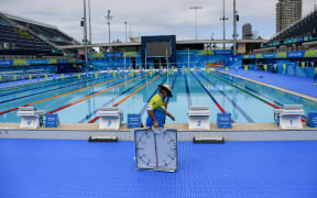 A volunteer carries a timing clock at the Optus Aquatic Centre ahead of the 2018 Gold Coast Commonwealth Games on March 30, 2018. / AFP PHOTO / YE AUNG THU