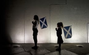 Two young girls holding saltires, watch the entertainment outside the Scottish Parliament in Edinburgh on September 18, 2014, during Scotland's independence referendum.