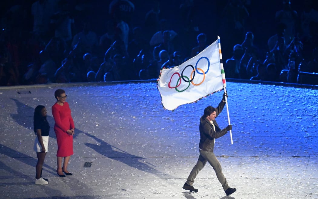American actor Tom Cruise receives the Olympic Flag to deliver it to Los Angeles during the Closing Ceremony of the 2024 Paris Olympic Games.