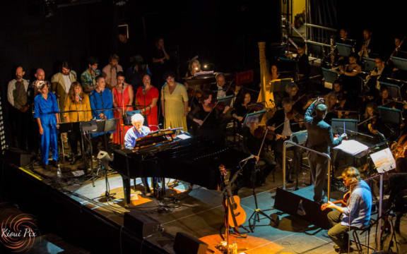 Neil Finn and APO on stage.