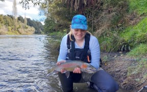 Fish and Game ranger Adam Daniel's daughter enjoying the trout caught in Whanganui River.