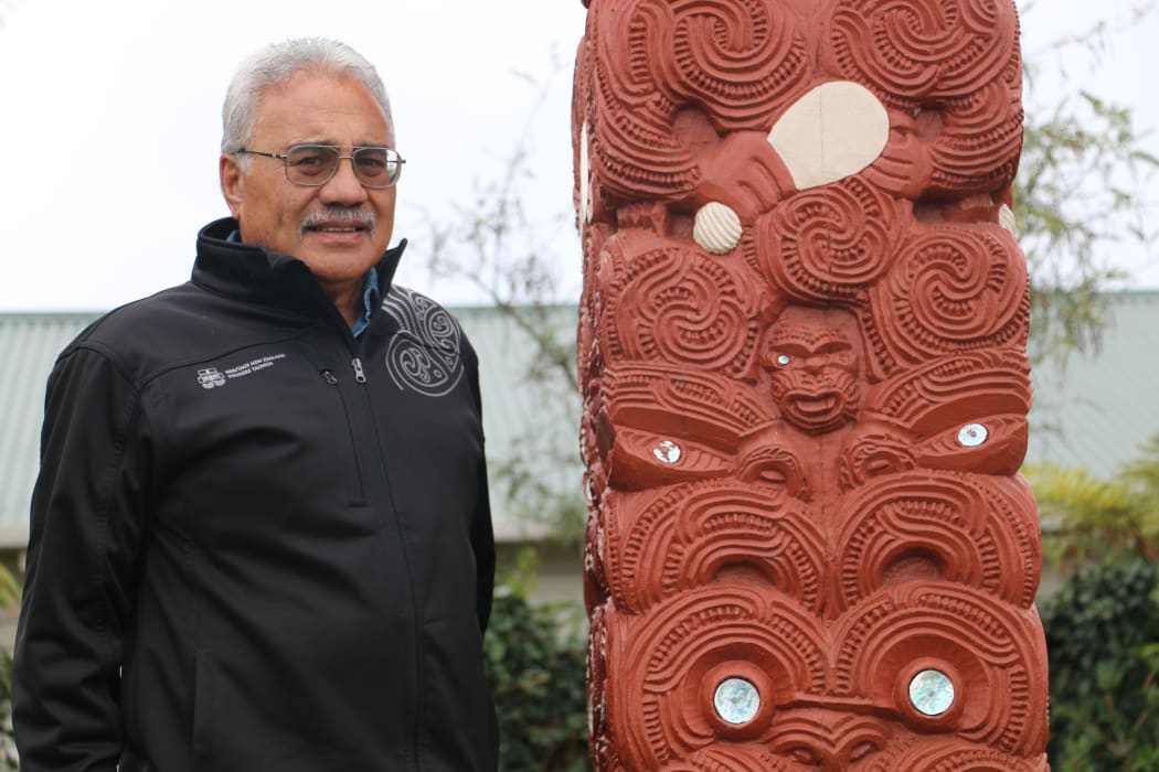 Jim Schuster next to the pou at Hinemihi near Whakarewarewa carved by Tene Waitere.