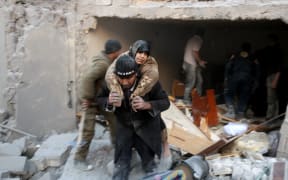 A rescuer carries a woman from the rubble of a building in Aleppo's rebel-held district of al-Hamra on 20 November.