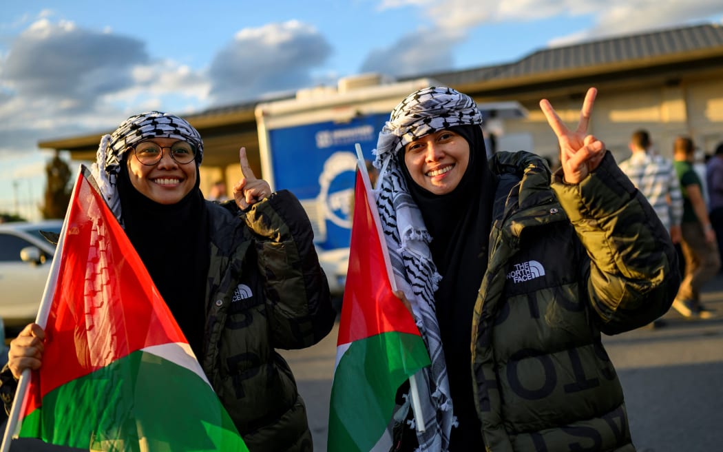 Sisters Nur Heliza Helmi (L) and Nur Hazwani Afiqah binti Helmi, two of the activists who were sailing aboard vessels from the Global Sumud Flotilla, make a victory sign after arriving with thirty-six Turks and nationals from 12 countries at Istanbul Airport on a special flight, after Israel stopped a Gaza-bound aid flotilla and detained hundreds of people, in Istanbul on October 4, 2025. "We expect 36 of our nationals on the Global Sumud Flotilla vessels seized by Israeli forces in international waters will return to our country this afternoon via a special flight," Turkish foreign ministry spokesman Oncu Keceli said on X, adding that the number has not been finalised. The Turkish diplomatic source said nationals from the United States, United Arab Emirates, Algeria, Morocco, Italy, Kuwait, Libya, Malaysia, Mauritania, Switzerland, Tunisia, and Jordan planned to be on the Turkish Airlines flight. (Photo by Yasin AKGUL / AFP)