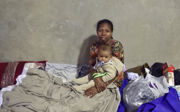 A woman and her baby take at a temporary cyclone shelter in the town of Ayr in far north Queensland.