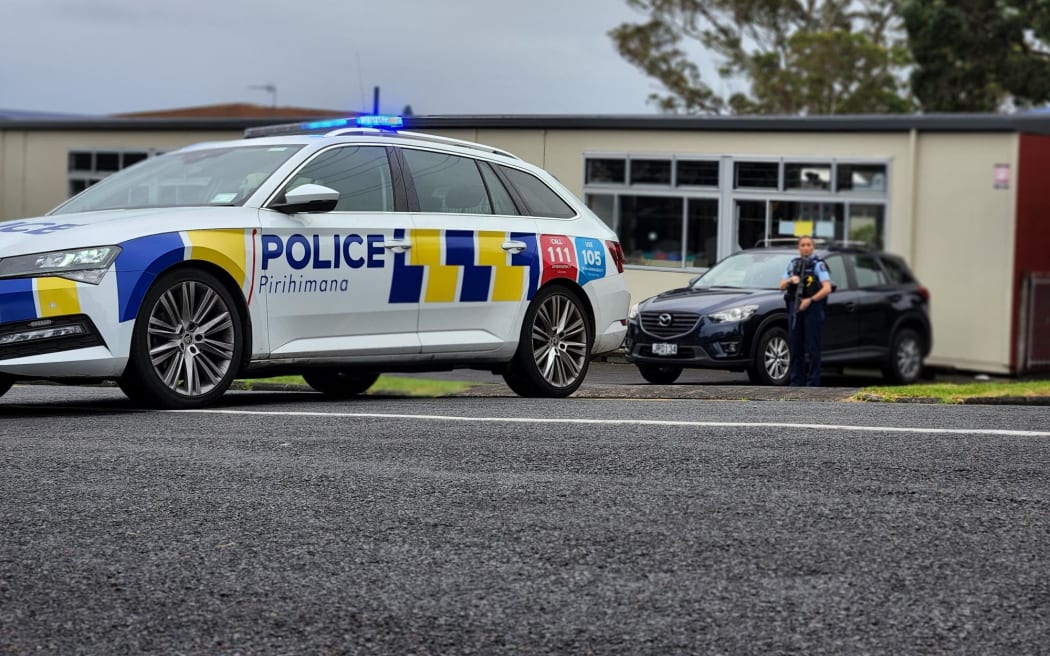 Armed police outside a school in Henderson, west Auckland, on 24 February 2024.