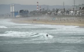 A surfer catches a wave in Manhattan Beach, California, on January 15, 2022. The US National Weather Service issued tsunami advisories for the entire west coast of the United States following a massive volcanic eruption across the Pacific Ocean in Tonga.