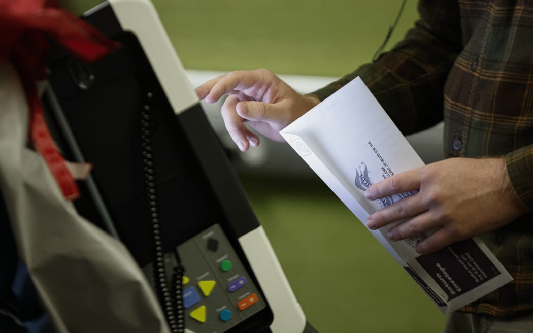A voter casts his ballot at an early voting polling location at the Madison Public Library Central in Madison, Wisconsin, on October 22, 2024. (Photo by KAMIL KRZACZYNSKI / AFP)