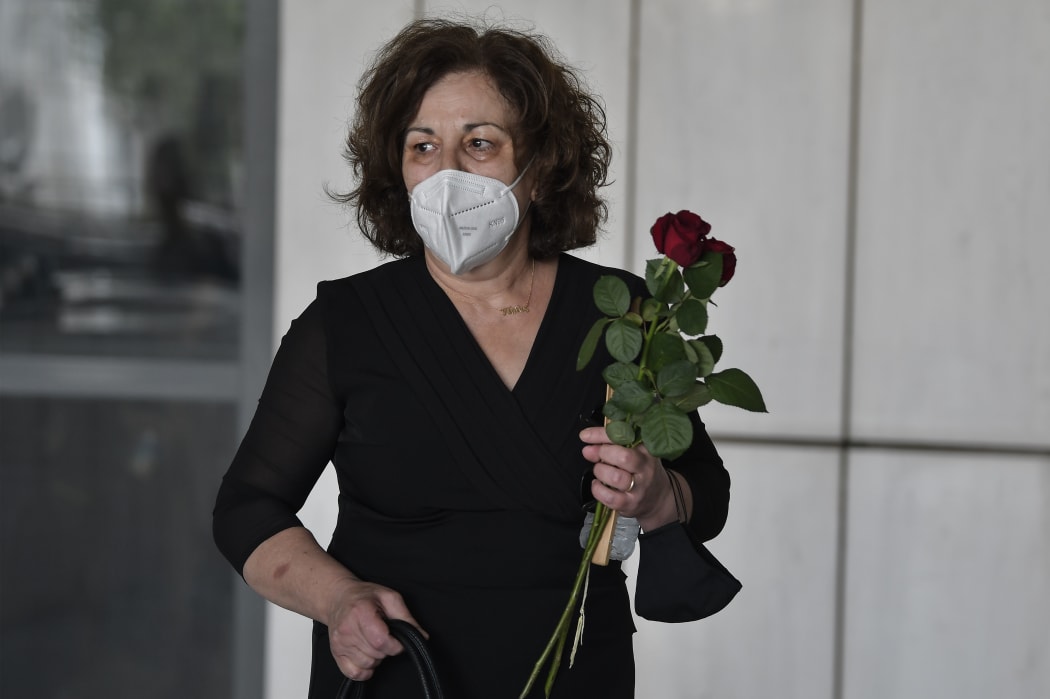 Magda Fyssa, the mother of murdered singer Pavlos Fyssas, holds a bunch of red roses as she arrives in court for the announcement of the verdict.