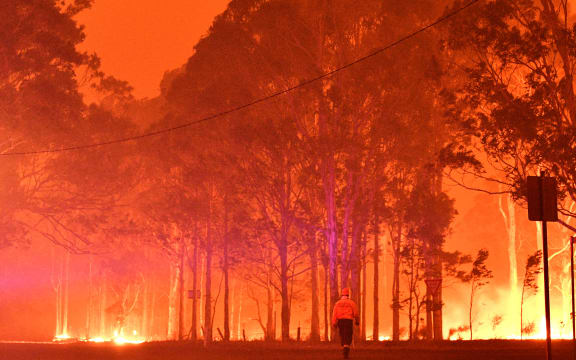A firefighter walks past burning trees during a battle against bushfires around the town of Nowra in the Australian state of New South Wales on December 31, 2019.