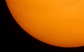 Mercury in silhouette, low center, as it transits across the face of the Sun on 11 November, 2019, from Washington, DC.