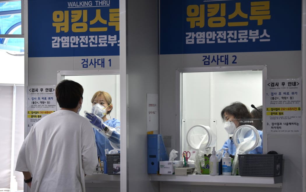 A medical staff in a booth takes test samples for the Covid-19 in Seoul on August 18, 2020.