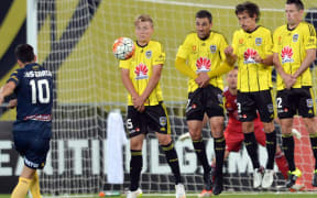Luis Garcia of the Mariners shooting a free-kick and James McGarry, Manny Muscat, Albert Riera Vidal and Blake Powell of the Phoenix (L-R) reacting.