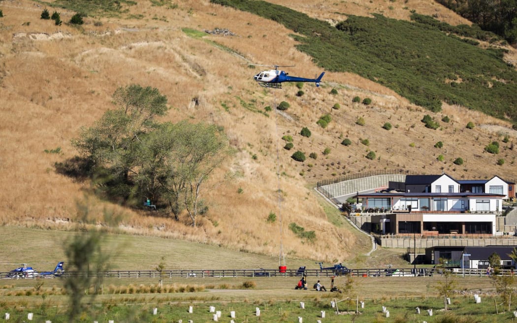Helicopters fill their monsoon buckets to fight the blaze n the Port Hills, 14 February 2024.