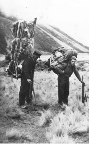Men carrying deer skins on back