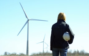 Woman engineer or architect with white safety hat and wind turbines on background