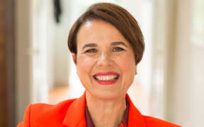 Galia BarHava smiles, wearing a bright orange suit.