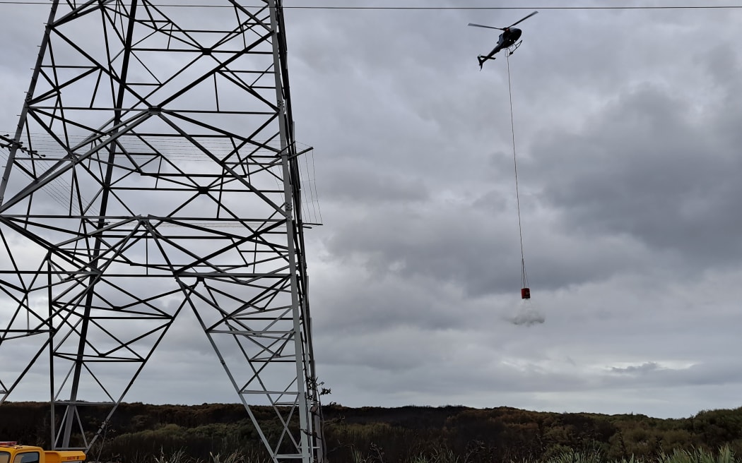 A helicopter supporting ground crews to extinguish hotspots at the Tiwai Road fire in Awarua this morning.