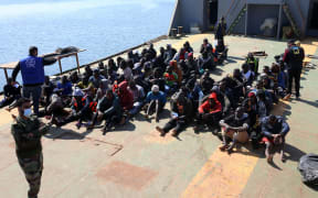 Rescued migrants sit aboard a Libyan coastguard vessel arriving at the capital Tripoli's naval base on 28 February, 2021.
