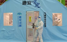 A staff member wearing personal protective equipment works at a temporary Covid-19 testing facility in north China's Tianjin on January 11, 2022, after authorities ordered the testing of all 14 million residents.