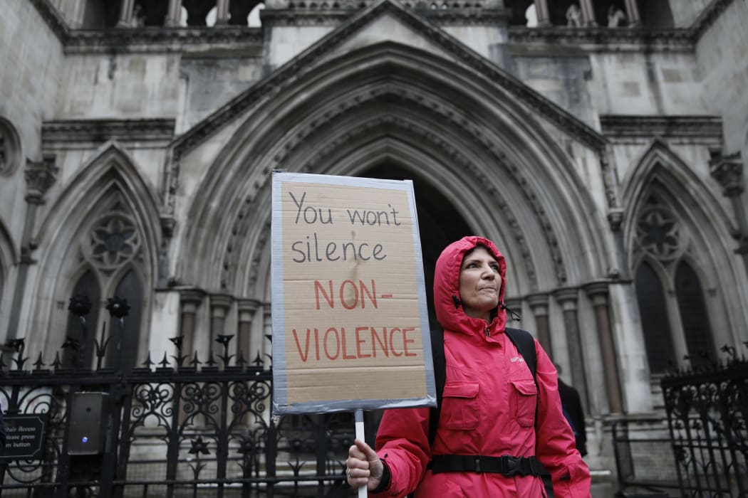 A supporter of climate action group Extinction Rebellion holds a placard outside the Royal Courts of Justice that houses the High Court in London on 24 October, 2019.