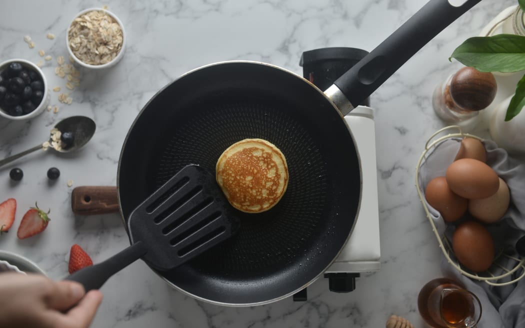 Flip the pancakes with a spatula. Concept of Cooking ingredients and method on white marble background, Dessert recipes and homemade.