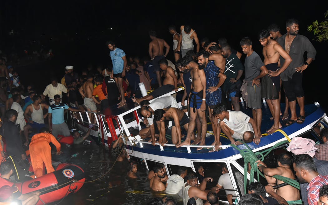 In this photograph taken on May 7, 2023, people carry out rescue operation at the site of a boat accident in Tanur, in Malappuram district of India's Kerala state. - At least 20 people died when a double-decker tourist boat capsized in India's southern state of Kerala late on May 7, authorities told local media. (Photo by AFP)
