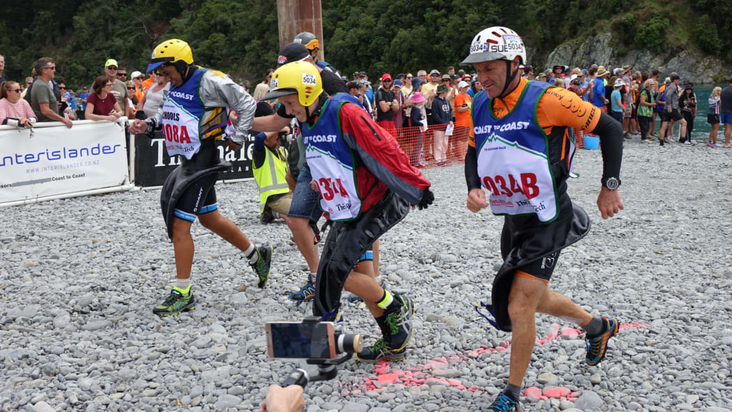 Bryce Adamson, second from right, and Taitama Tukaki, third from right, race to their bikes after completing the kayak section.
