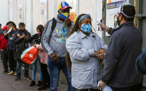 A worker checks the temperature of a customer, outside a supermarket in Valparaiso, Chile, on 12 June 2020.
