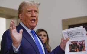Former US president Donald Trump displays a media article outside the New York State Supreme Court on the first day of his civil fraud trial, in New York City on October 2, 2023.