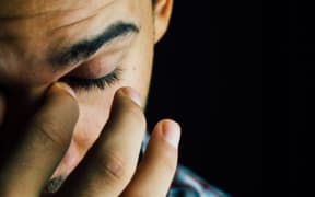 close up of man in cap touching his eyes