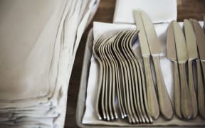 [England] High angle close up of napkins and silver forks and knives on a table in a restaurant. (Photo by Mint Images / Mint Images / Mint Images via AFP)