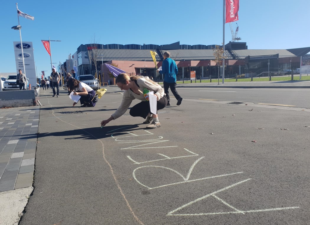 Jamie Stevenson helps draw an Extinction Rebellion mural connecting the Christchurch City Council and regional council offices.