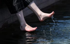 A young woman cools off her feet in a fountain  on a hot spring day, in Moscow,