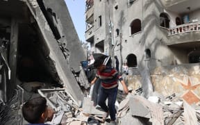 Children walk through the rubble of a destroyed building in a residential area in Deir al-Balah in the central Gaza Strip on 7 April, 2025, following overnight Israeli airstrikes.