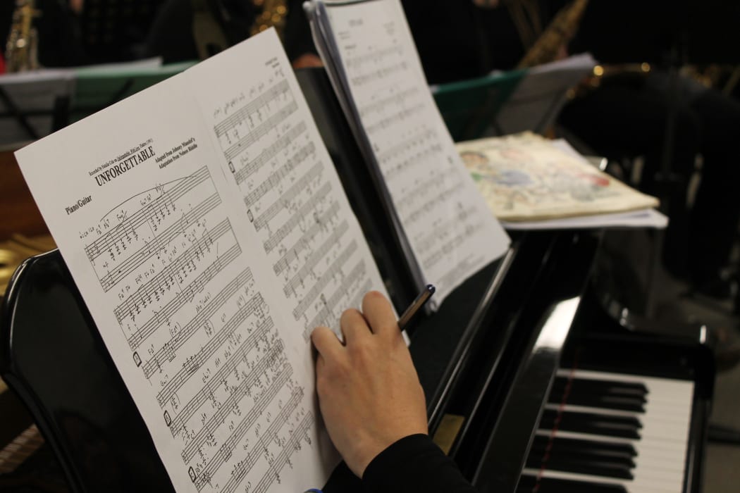 A photo of sheet music for "Unforgettable", a song by Natalie Cole. The band is planning a tribute to the artist.